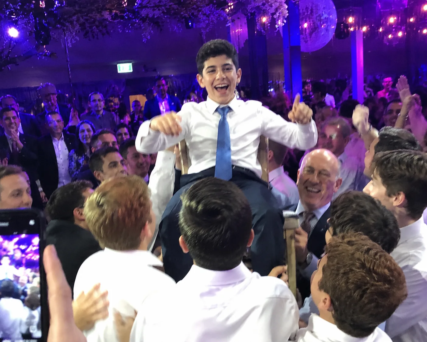 A Bar Mitzvah celebration with family gathered around the guest of honour