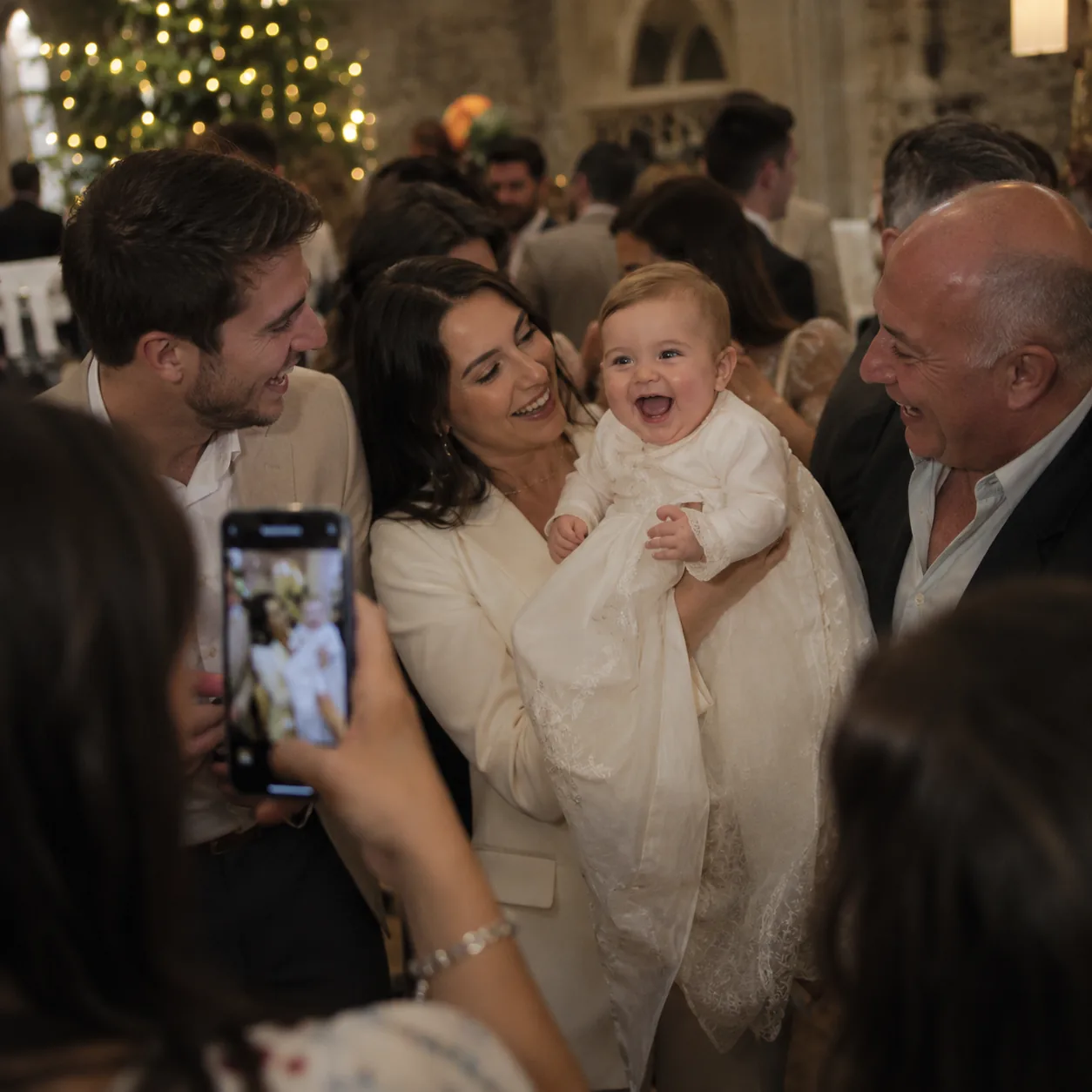 A baby at a christening surrounded by family